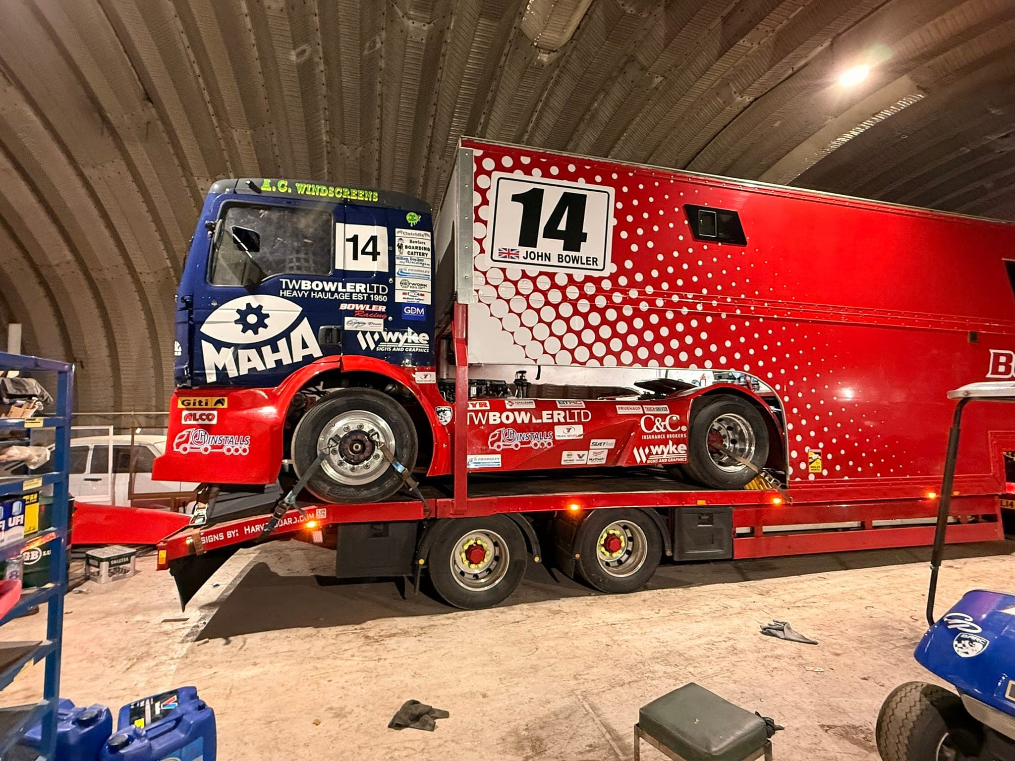 Diana, number 14, strapped onto the bed of the red team transporter inside an arched workshop, ‘14 John Bowler’ on the transporter box