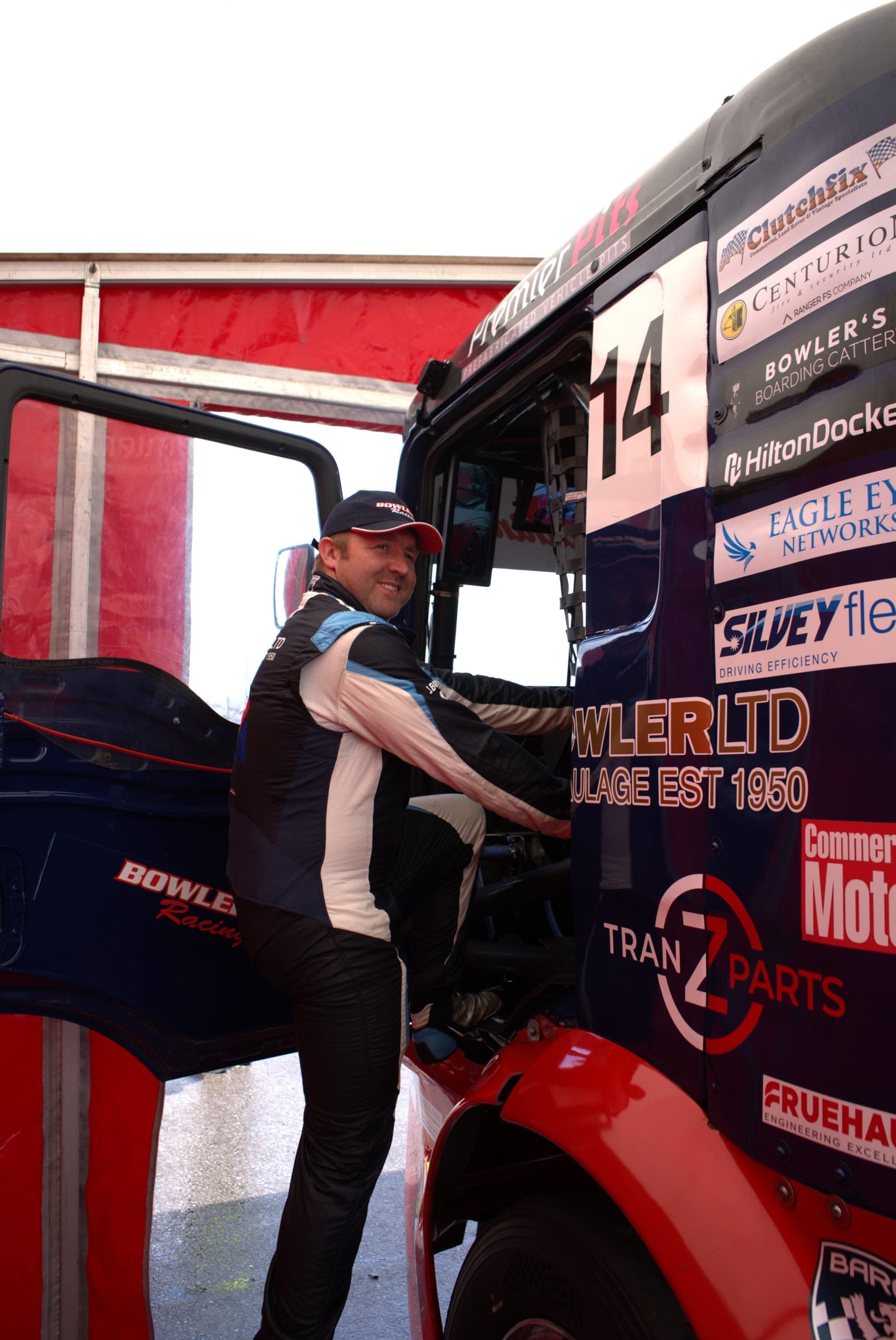 John Bowler smiling at the camera as he climbs into Diana’s cab under the red team awning